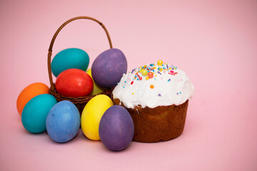 Small basket with beautiful colorful Easter eggs and Easter cakes