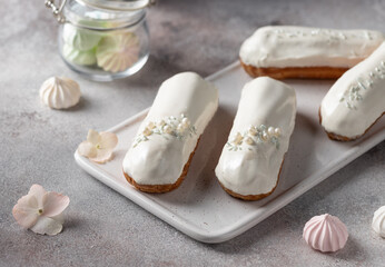 white glaze eclairs on white serving board. Delicious French dessert. selective focus