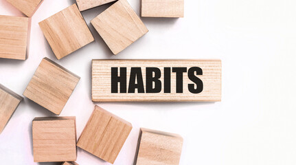 On a light background, wooden cubes and a wooden block with the text HABITS. View from above