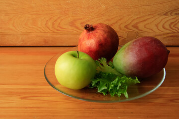 Pomegranate,mango,green apple on a transparent plate.