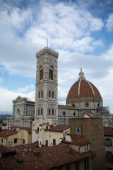 Fototapeta premium vista del duomo di firenze visto da vicino sopra i tetti delle case, di giorno con nuvole bianche in cielo