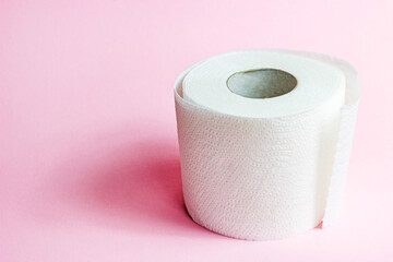White toilet paper roll on light pink background with copy space.