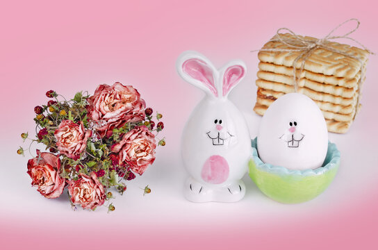 An Easter bunny and an egg with a face on a pink and white background. The concept of Easter