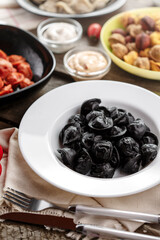 Black color dumplings on wooden table with souce