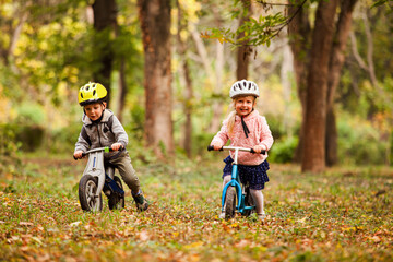 Plakat Cheerful preschool kids outdoors on balance bikes