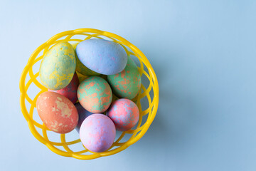 Yellow basket with colored eggs. Easter concept. Copy space.