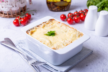 Lasagna with bolognese and bechamel sauce in white portion form. Traditional Italian dish, homemade. Close-up.