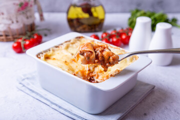 Lasagna with bolognese and bechamel sauce in white portion form. Traditional Italian dish, homemade. Close-up.