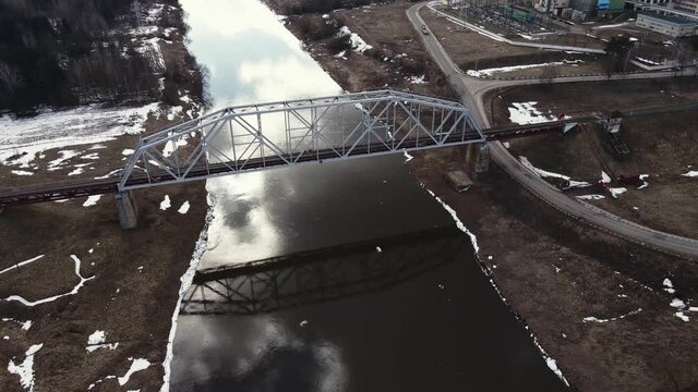 Metal railway train bridge over the river
Belarus Orsha Dnieper River. 
early spring Aerial footage from drone orbital take off from the bridge. downsizing landscape