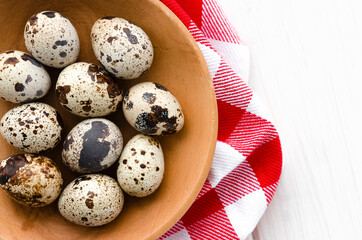 The quail eggs lie on a wooden plate on a white table