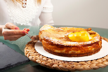 Woman's hands with pink nails serving a slice of lemon cheesecake with cinnamon