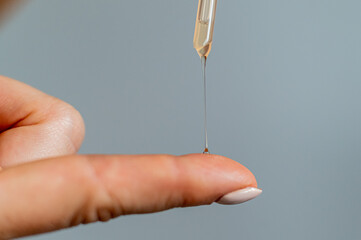 Close-up woman dripping oil on her finger over white background