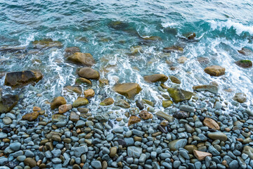 Photo of the surf. Blue water foams among yellow and blue stones