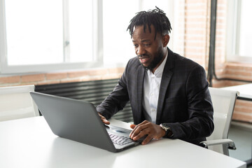 handsome adult african man at table with laptop at work 