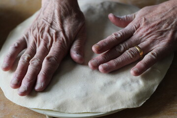 Old Woman hands in process of making Russian dumplings. Russian cuisine meat dish consisting of minced meat and dough