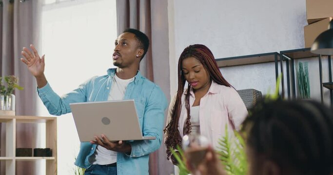 Adorable satisfied modern young african american couple with kids standing in their newly acquired apartment and planning how to furnish dweling to their preferences