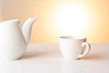 A cup for coffee with a kettle on a background with warm light.