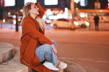 young woman sitting on steps in the city at night 