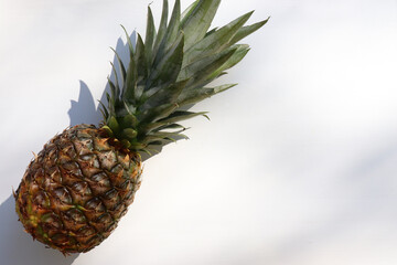 Exotic tropical fruit pineapple on white table. Top view, copy space. Hard light, shadow. Summer background