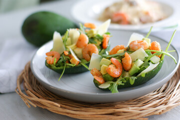 Delicious salad with shrimp, avocado, arugula, parmesan cheese in avocado boats.