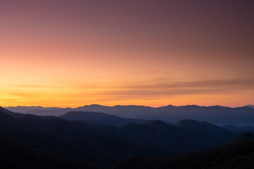 Fototapeta na wymiar Faint Clouds Hang Over Mountain Ridges At Sunrise