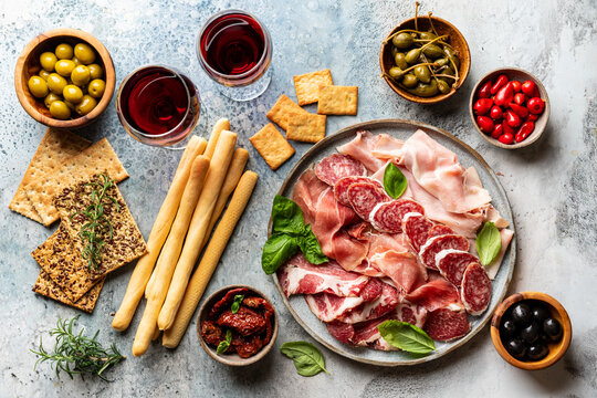 Appetizers With Differents Antipasti, Charcuterie, Snacks And Red Wine. Sausage, Ham, Tapas, Olives And Crackers For Buffet Party. Top View, Flat Lay