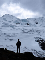 Silhouette of man admiring huge white ice snow mountain in  cordilera Huaytapallana, Huancayo, peru