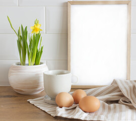 Spring, Easter breakfast still life. A cup of milk, narcissus, daffodil flowers, hen eggs, and empty picture frame mockups. Linen tablecloth. Farmhouse, Scandinavian interior.