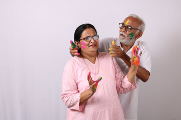 indian senior or old aged couple celebrating holi with colour 