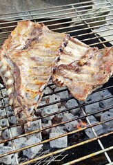 Barbecue  baby back or pork spareribs cooking on a charcoal grill. 