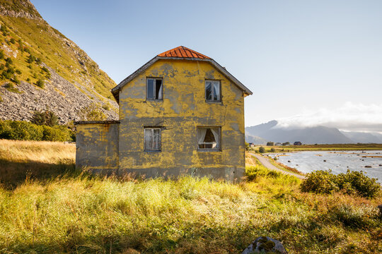 Dilapidated small yellow house with four windows in Lofoten, Norway