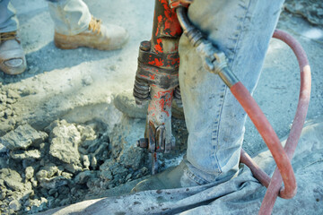 Using proper safety technique, a construction worker prepares to us a jackhammer to break up concrete