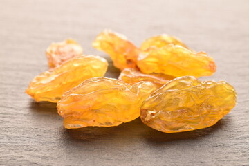Yellow-golden organic raisins, close-up, on a slate board.