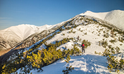Hiker going up the snowy mountains on a sunny day