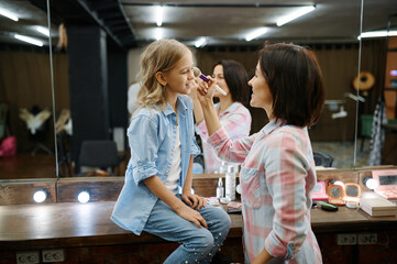 Mother and daughter doing makeup in salon