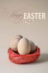 Easter eggs in a decorative nest on a neutral pastel background. Minimalistic trendy close up composition. Greeting card with text Happy Easter 