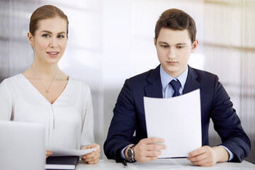 Obraz premium Business people discussing something while sitting in sunny office. Focus at businesswoman while talking to her male colleague