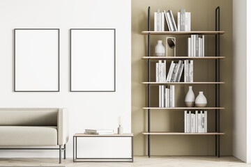 Light modern living room interior furnished by beige sofa, coffee table, bookshelf and two blank...