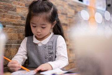 Back to school. Happy smiling pupil drawing at the desk. Cute little preschooler child drawing at home. Kid girl drawing with pencils