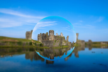 Caerphilly Castle near Cardiff UK in the spring sunshine seen through a floating glass crystal ball. - obrazy, fototapety, plakaty
