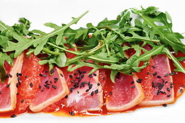 Salmon served with a grapefruit sauce, arugula and black sesame seeds