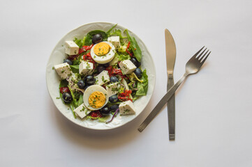 white plate with salad, knife, fork, isolated on white background