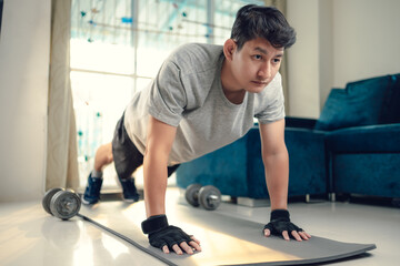 Fototapeta na wymiar Young man doing push up and exercises on yoga mat in living room at home. Fitness, workout and traning at home concept.