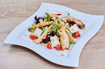 Salad mixed of soft cheese, greens, almond, fried chicken fillet, cherry tomatoes and pear 