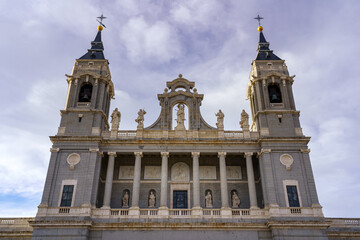 Main facade of the Almudena cathedral in Madrid on sunny day with clouds.