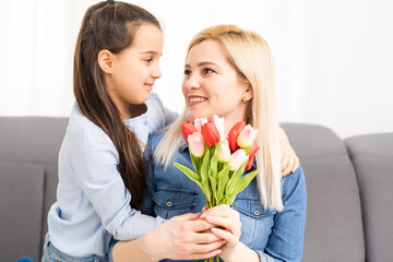 child daughter congratulates mother and gives a bouquet of flowers tulips