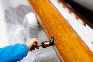 Varnishing the wooden mast of a classic sailing yacht