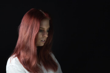 Side view low key portrait of beautiful young woman looking down ahead. Horizontally. 