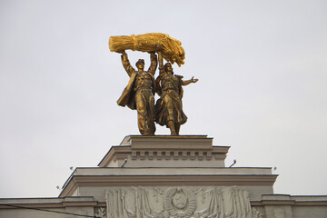 MOSCOW, RUSSIA-FEBRUARY 2020: Gilded figures of a tractor driver and a collective farmer close-up at the top of the arch of the Main Entrance to the VDNH in Moscow