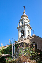 The bell tower of the ancient temple against the blue sky.